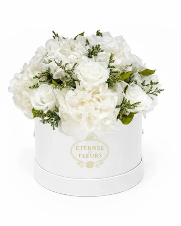 White roses flowers in a round white box with 'Eternel Fleurs' branding on a white background